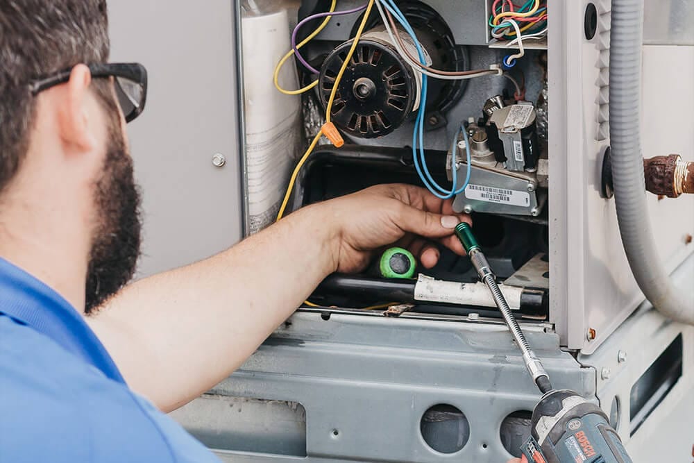 HVAC technician performing air handler maintenance in DeKalb home