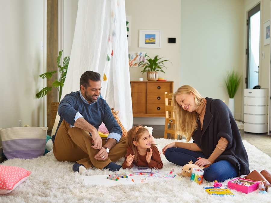 Family in room playing with air filtration system in background.