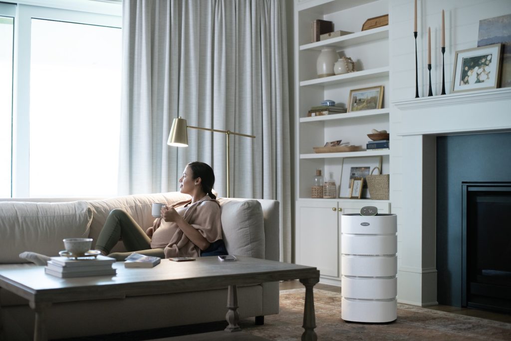 Lady on couch next to air purifier. 