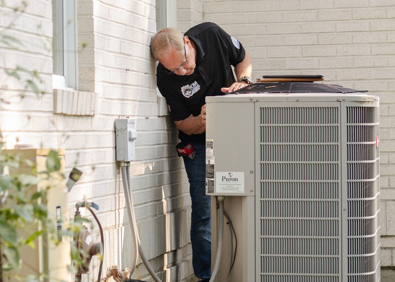 Dave from KM heating and cooling inspecting a unit for AC replacement at a residential home.