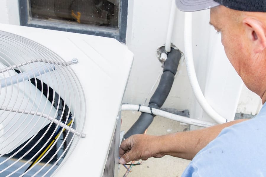 Professional HVAC technician inspecting AC system for replacement in DeKalb home
