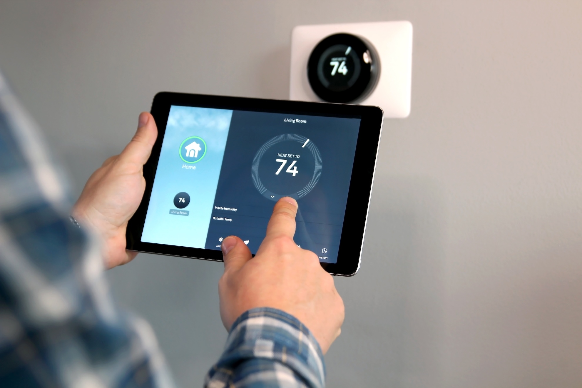 someone changing the temperature on their iPad connecting to their smart wifi thermostat.